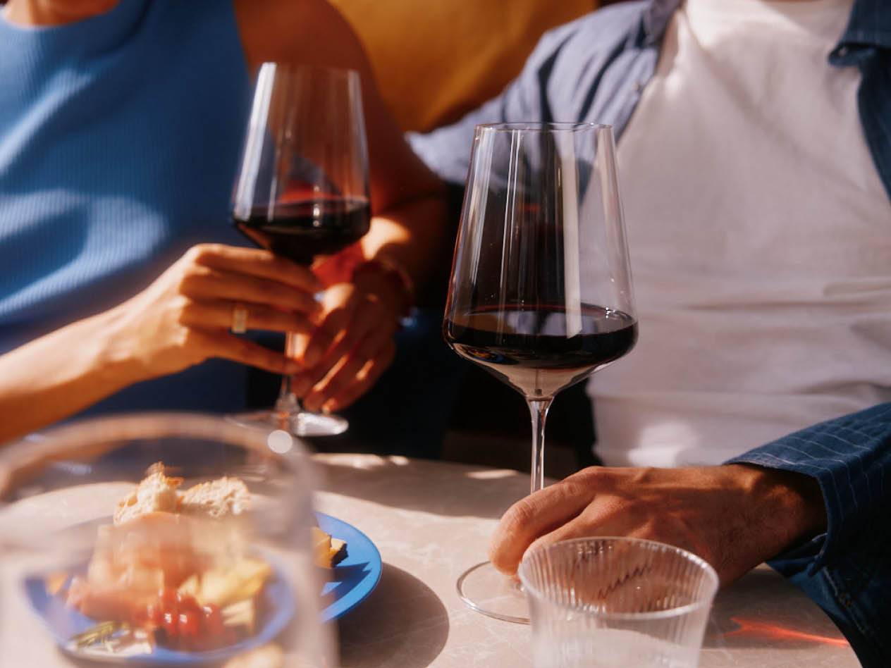 Zwei Personen genießen ein Glas Rotwein.