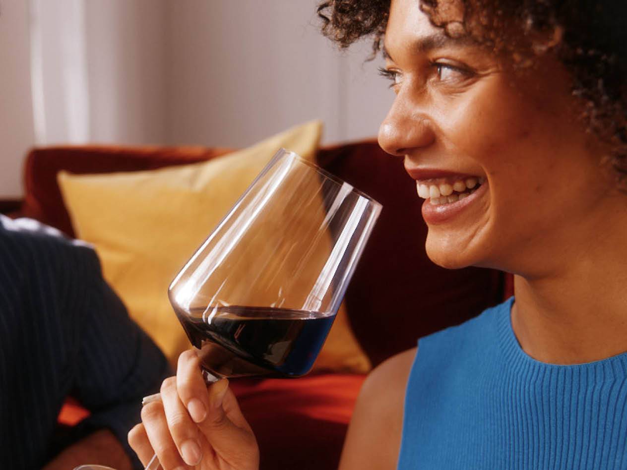 Eine Frau genießt einen Rotwein aus einem eleganten Glas.