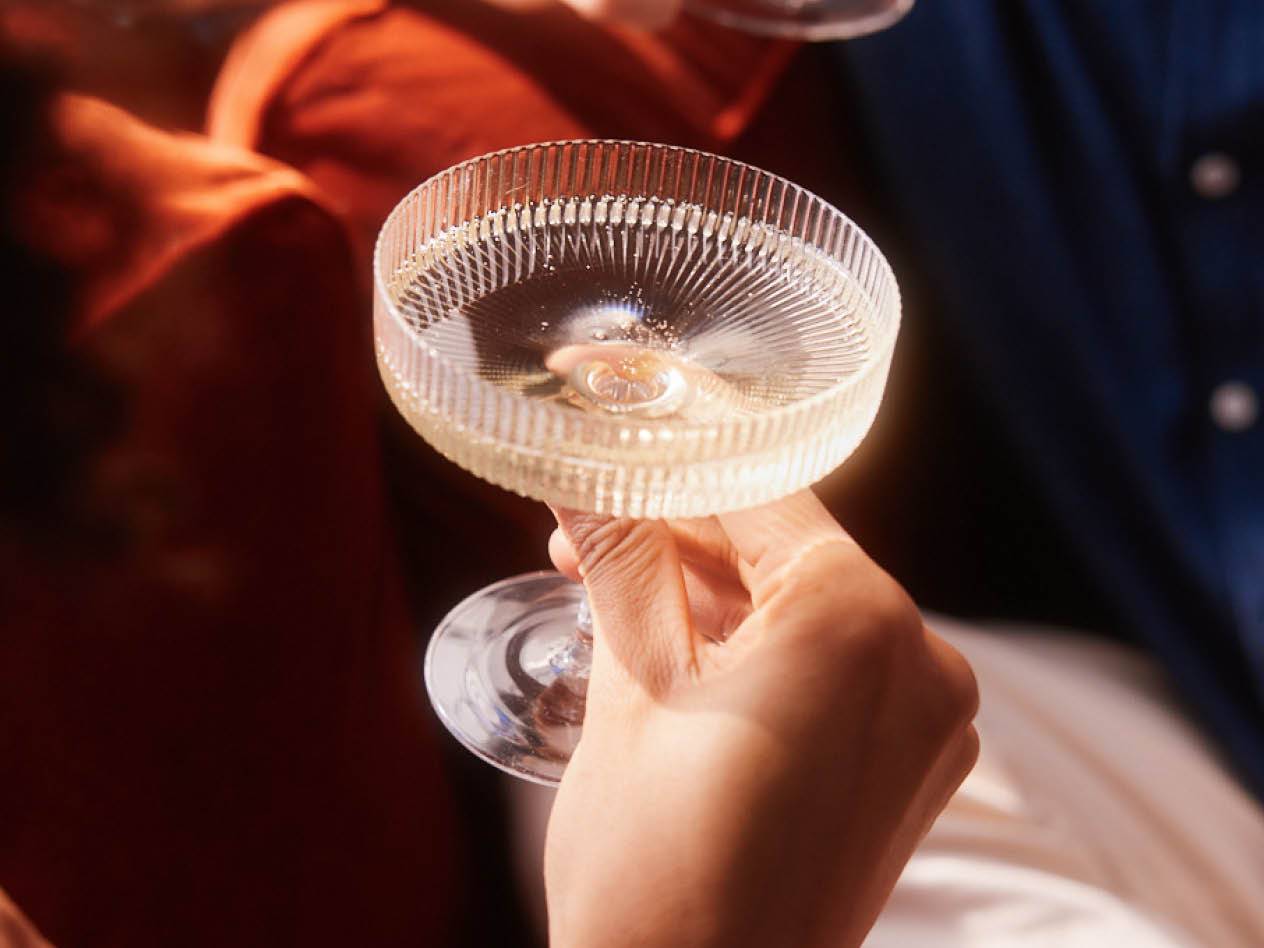 Eine Hand hält ein Glas Sekt.