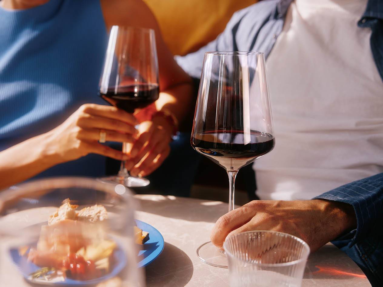 Zwei Personen genießen einen Rotwein und einen Snack.
