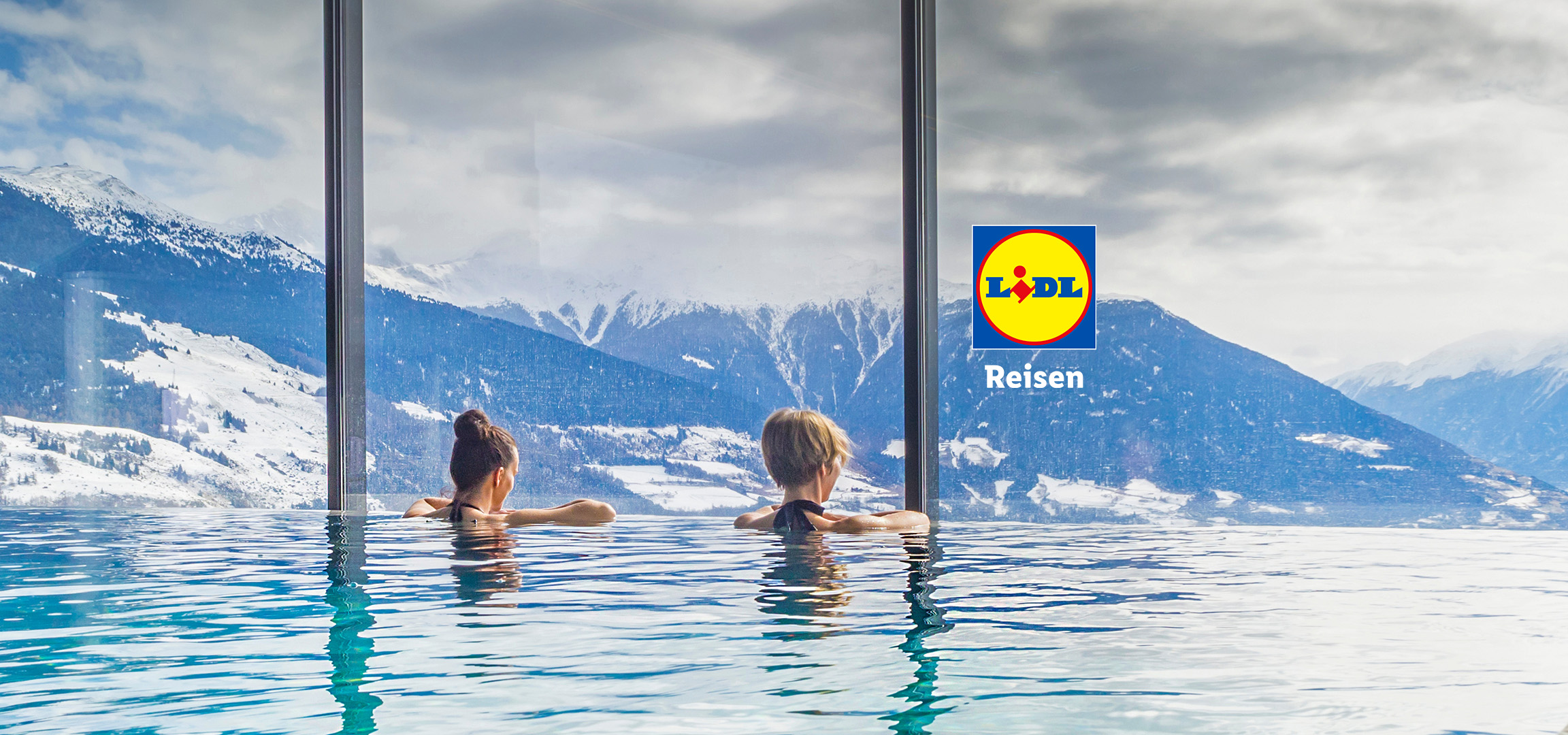 Lidl Reisen: Zwei Personen entspannen in einem Infinity-Pool mit Blick auf verschneite Berge.
