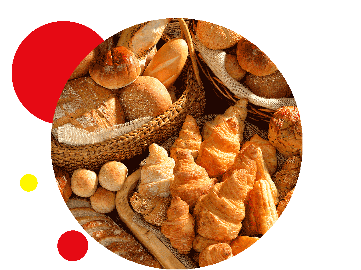 Eine Auswahl an Brot, Brötchen und Croissants in einem Korb und auf einem Tisch.