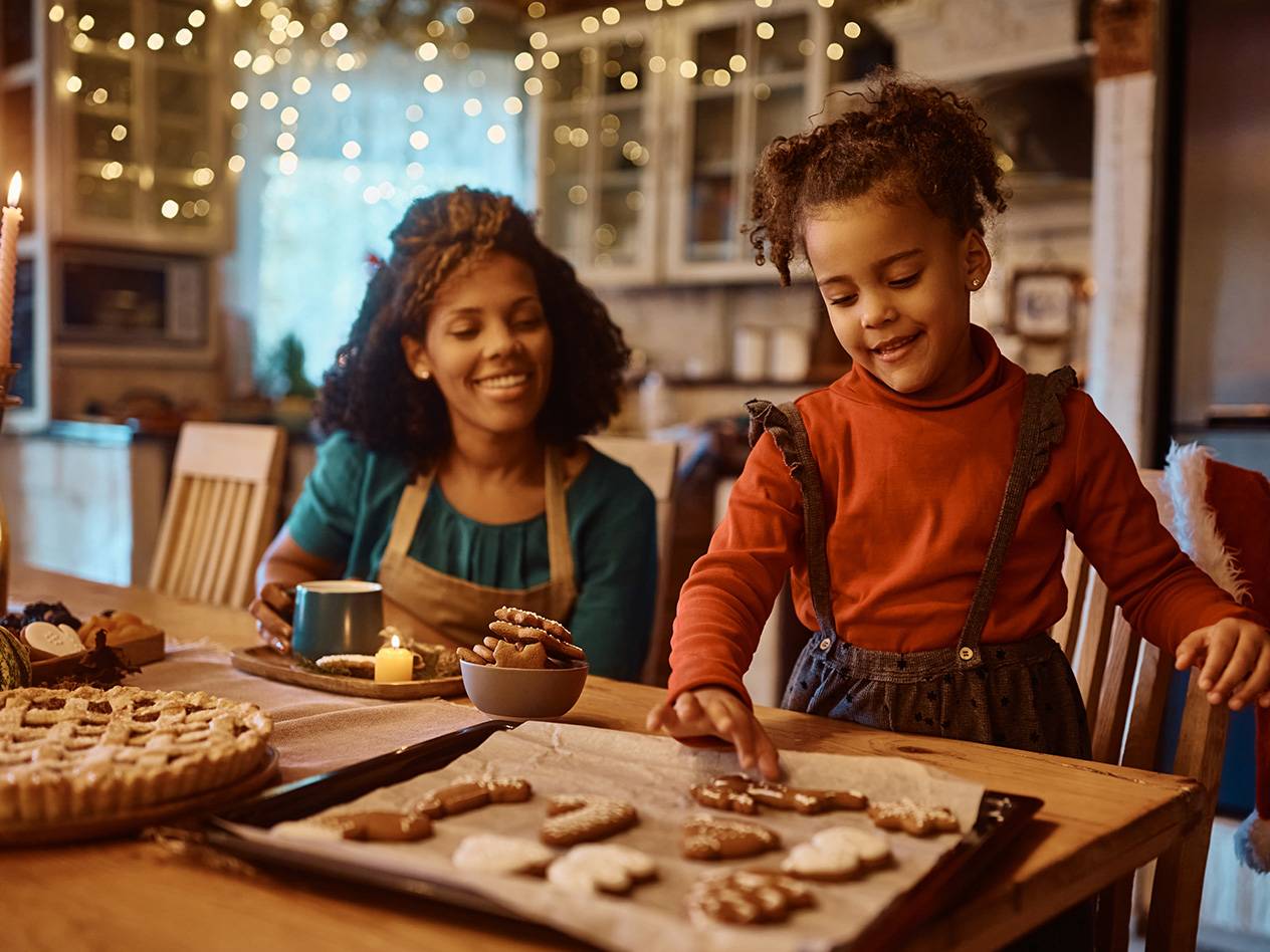 Mutter und Kind backen Weihnachtsplätzchen und Kuchen in einer festlich dekorierten Küche.