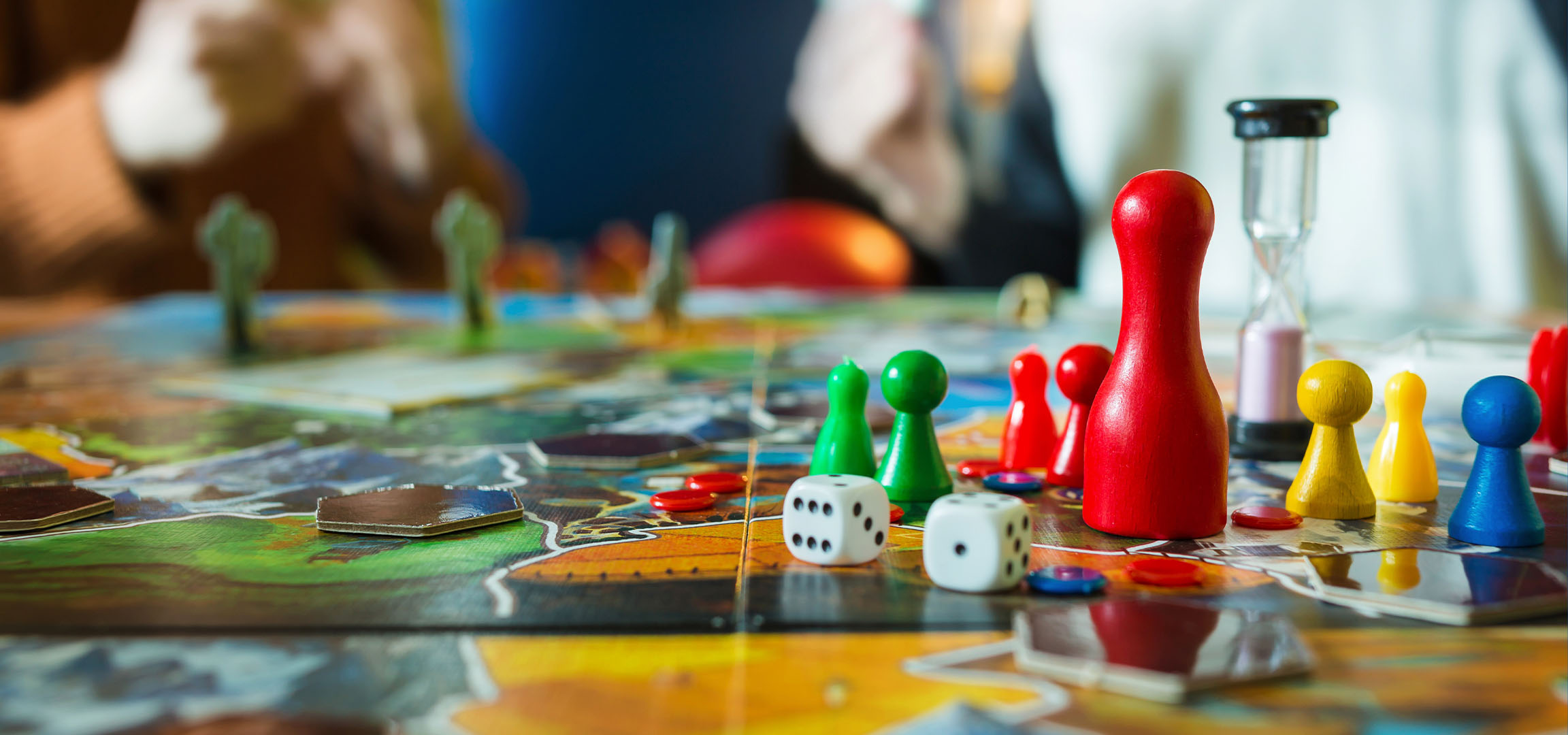 Bunte Brettspielfiguren, darunter rote, grüne, gelbe und blaue Bauern, mit Würfeln.