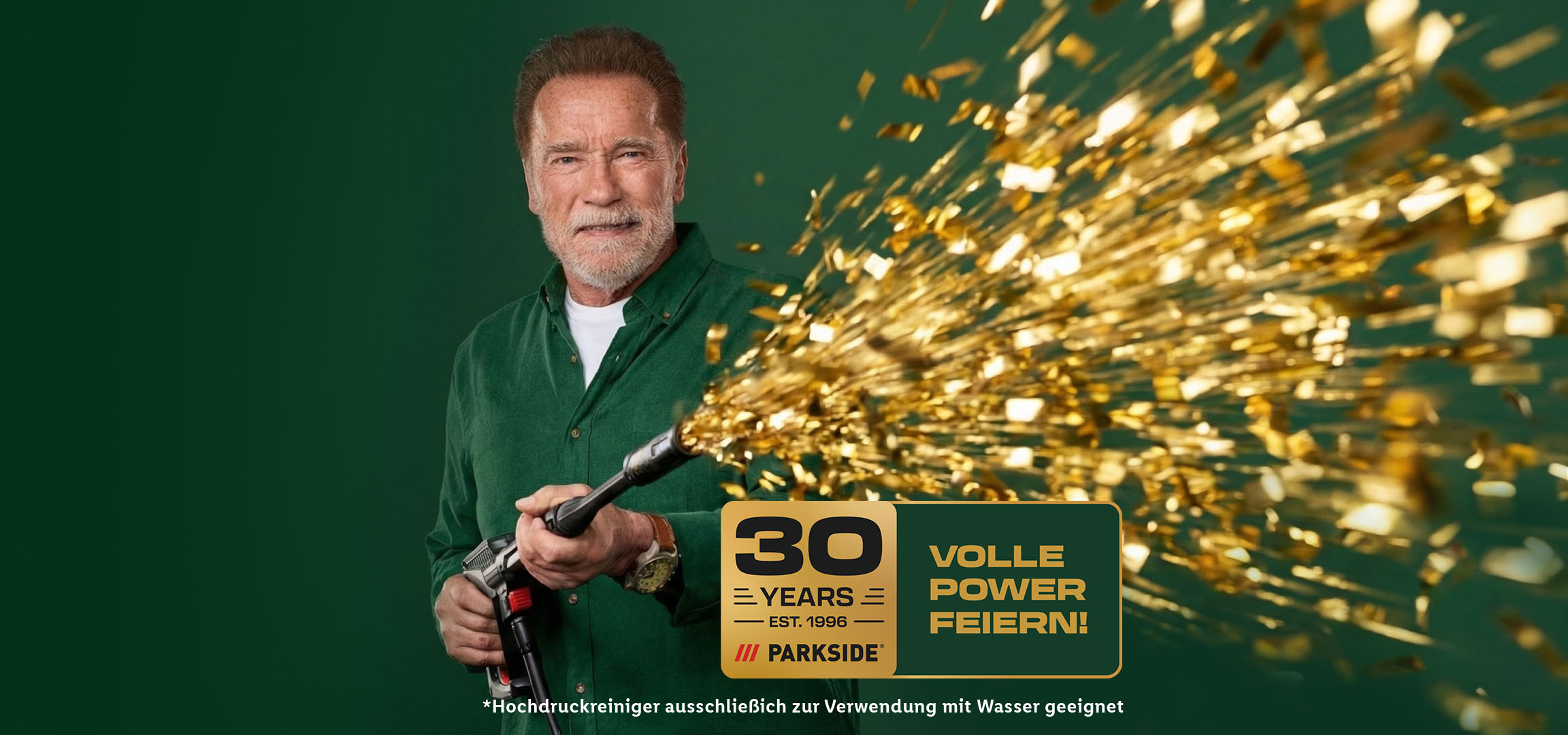 Bärtiger Mann in grünem Hemd schießt goldenes Konfetti, feiert 30 Jahre mit voller Power.
