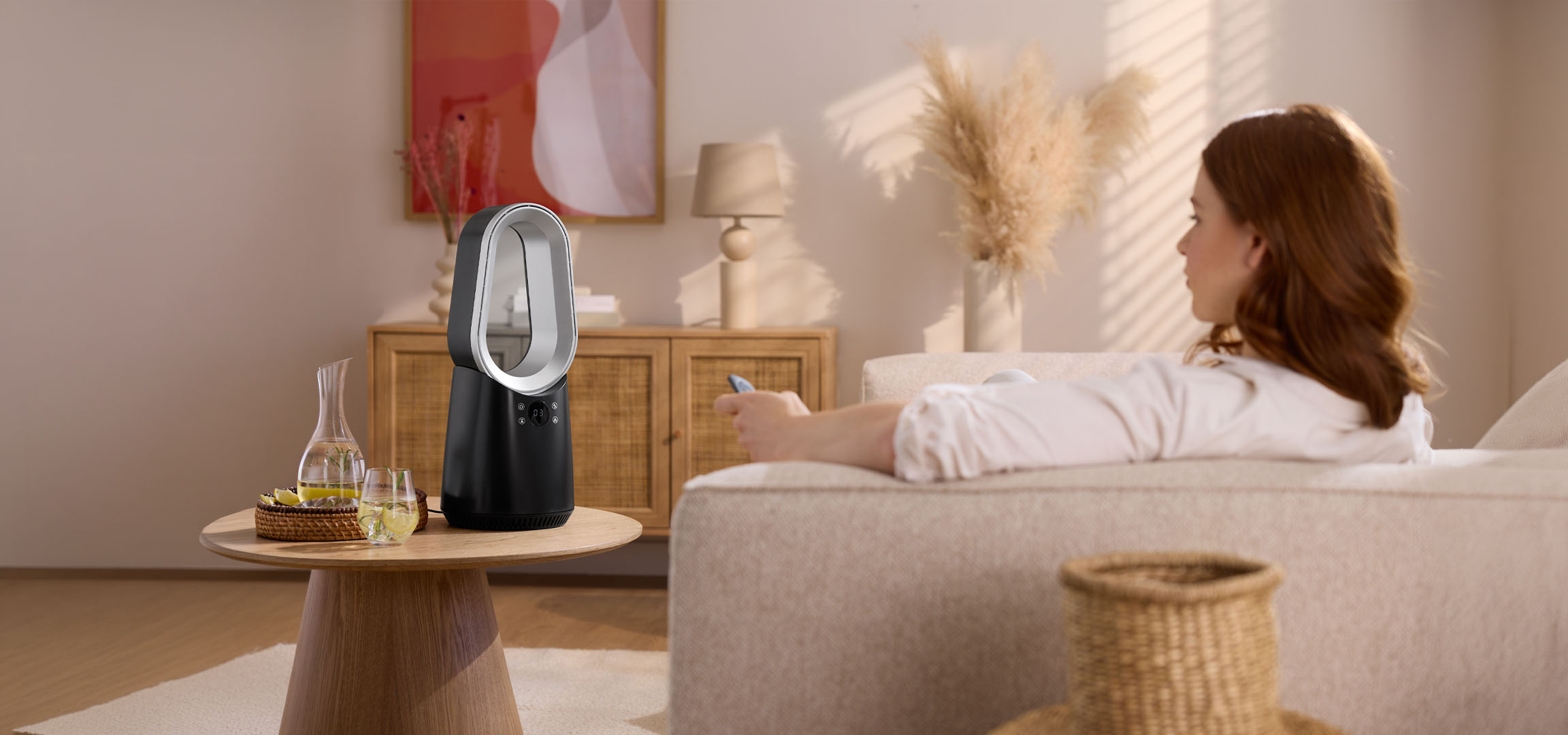 Frau auf Sofa mit Fernbedienung, moderner Ventilator und Getränke auf Tisch.