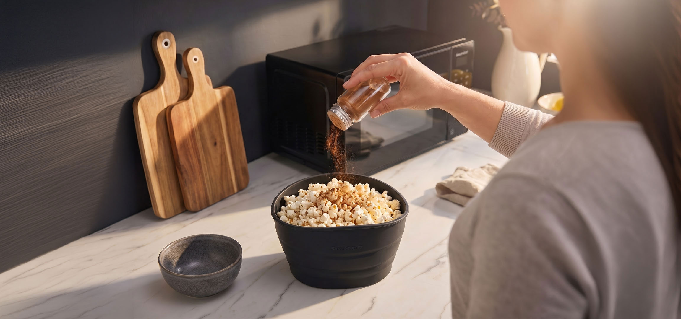 KI-generiert: Popcorn in einer schwarzen Schüssel, gewürzt mit Gewürzen, neben Holzschneidebrettern.