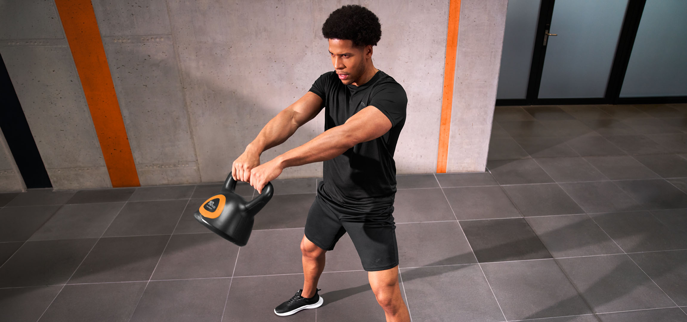 KI-generiert: Mann trainiert mit einer schwarz-orangen Kettlebell.