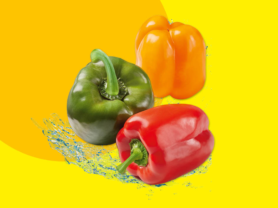 Drei Paprika in Rot, Grün und Orange mit Wasserspritzern auf gelbem Hintergrund.