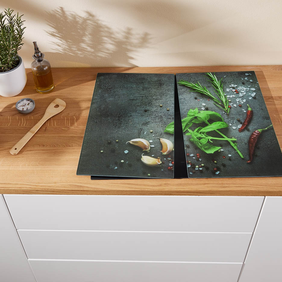 Zwei Herdabdeckplatten mit Gewürzen auf einer Küchenarbeitsplatte aus Holz.