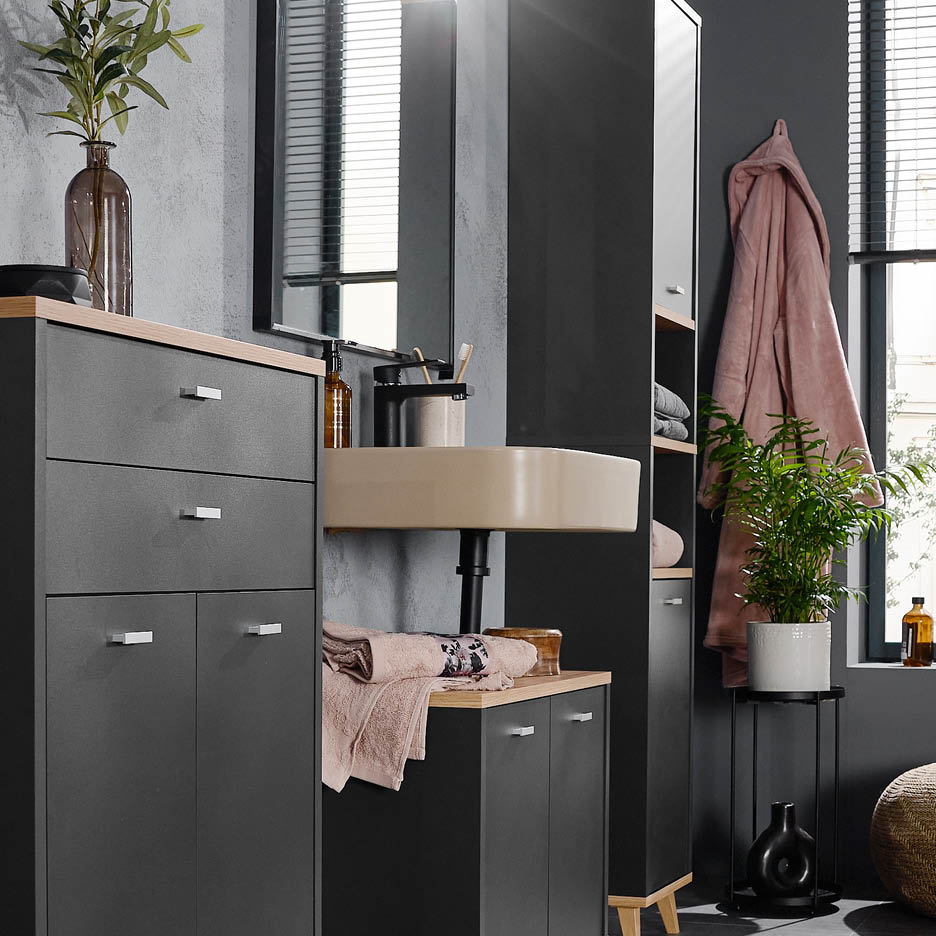 Modernes Badezimmer mit dunklen Schränken, hellem Waschbecken und Pflanzen.