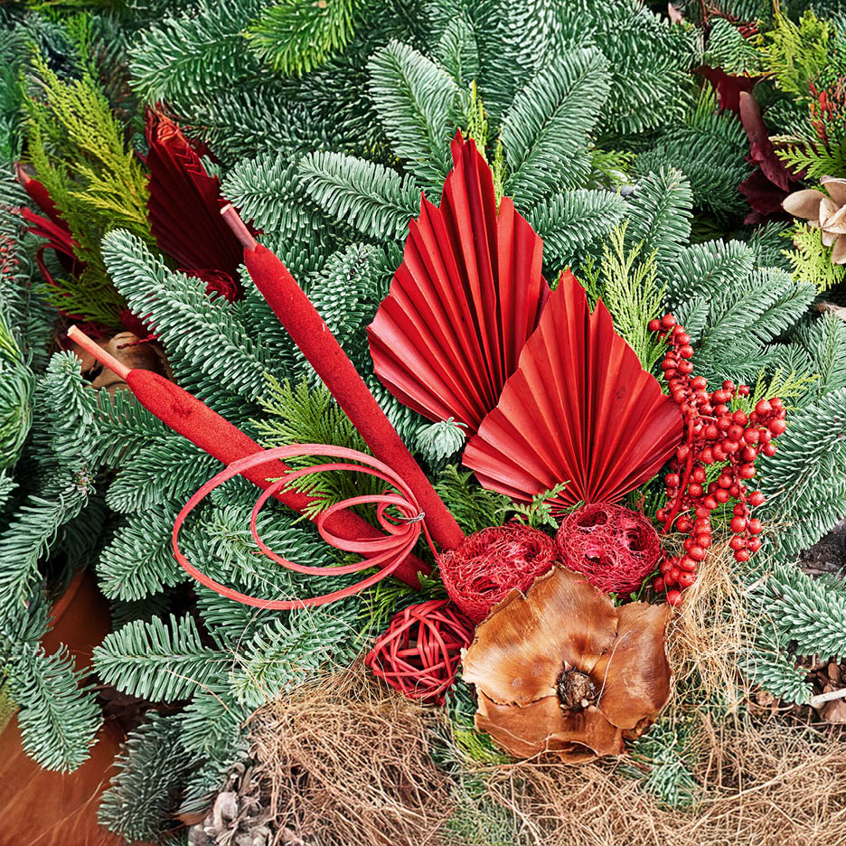 Weihnachtsdekoration mit roten Blättern, Beeren und Tannenzweigen.