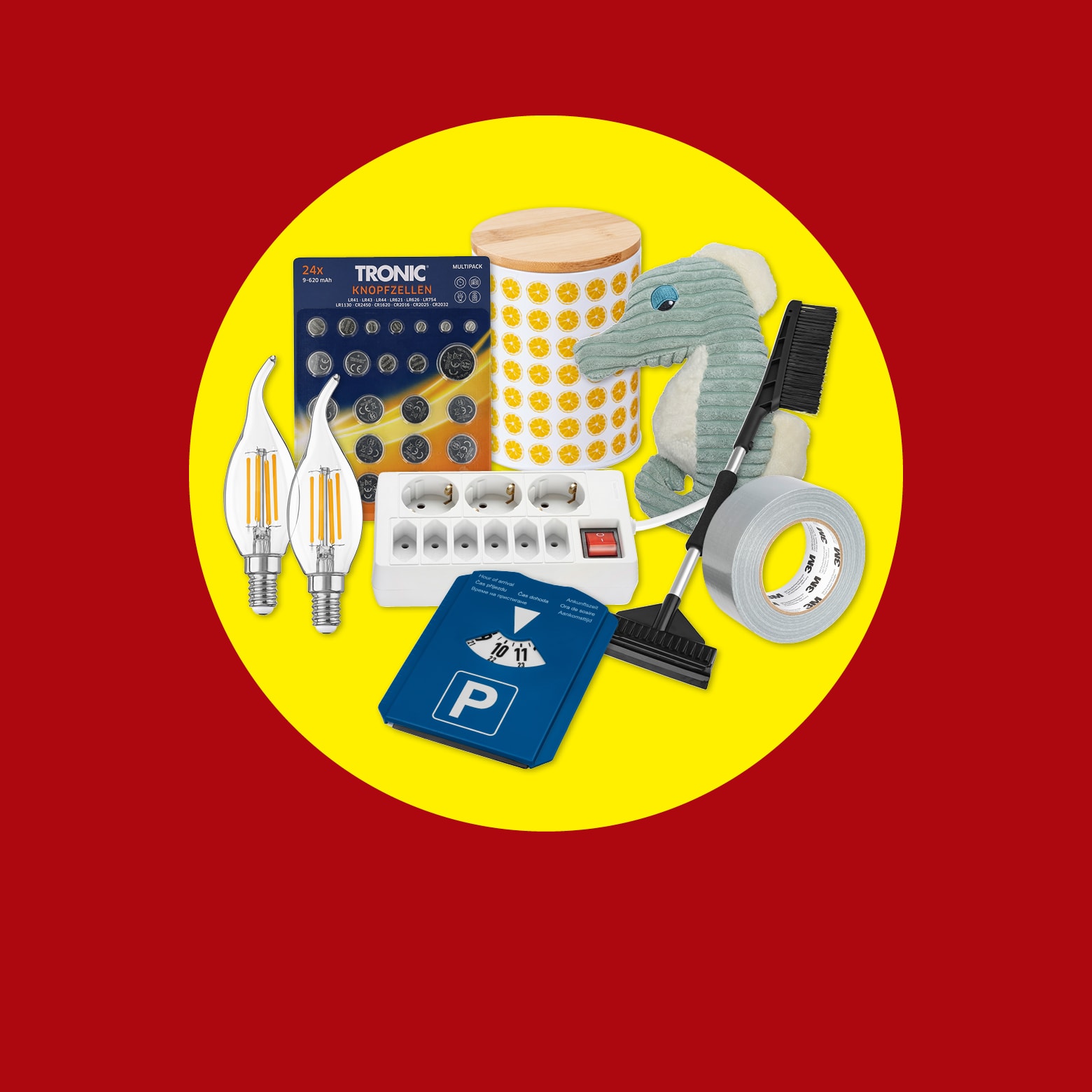 Eine Auswahl an Haushaltsartikeln, darunter TRONIC Knopfzellen, Glühbirnen, eine Steckerleiste, eine Parkscheibe, Klebeband, ein Plüschtier und eine Dose.