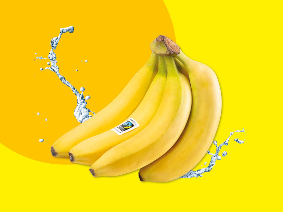 Eine Bananenstaude mit einem Fairtrade-Siegel und Wasserspritzern auf gelbem Hintergrund.