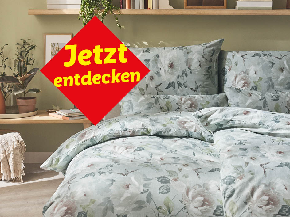 Bettwäsche mit Blumenmuster in einem Schlafzimmer mit Pflanzen und Holzregal.