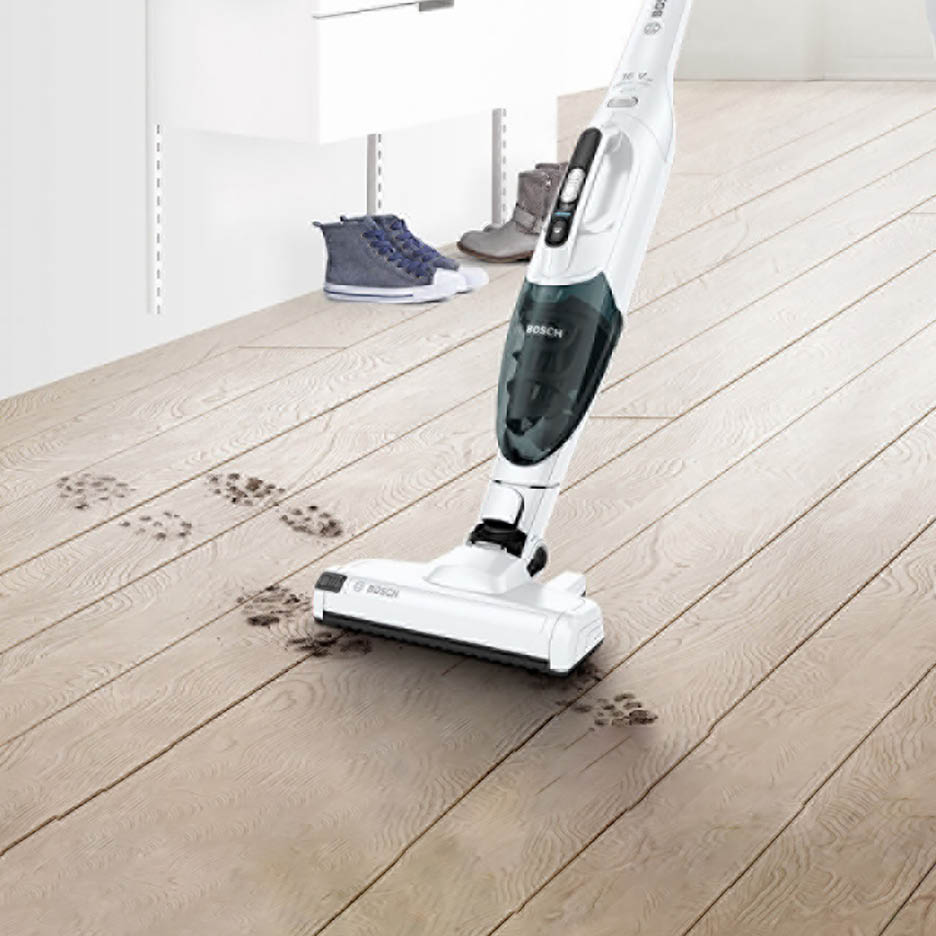Ein Bosch-Staubsauger reinigt schmutzige Fußabdrücke auf einem Holzboden.