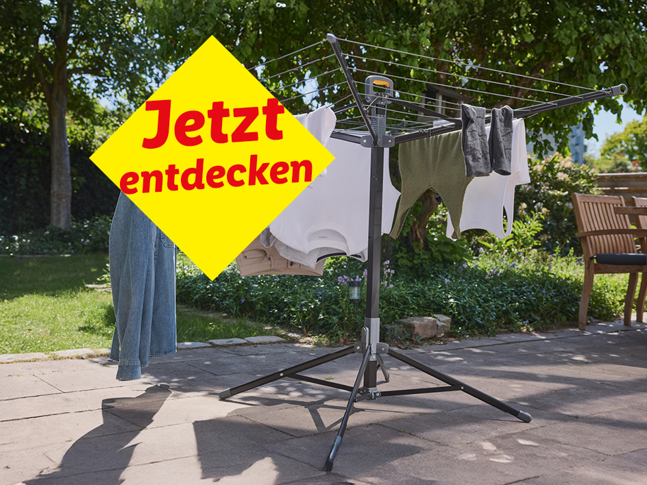 Wäscheständer mit Kleidung im Garten, mit gelbem Werbebanner „Jetzt entdecken“