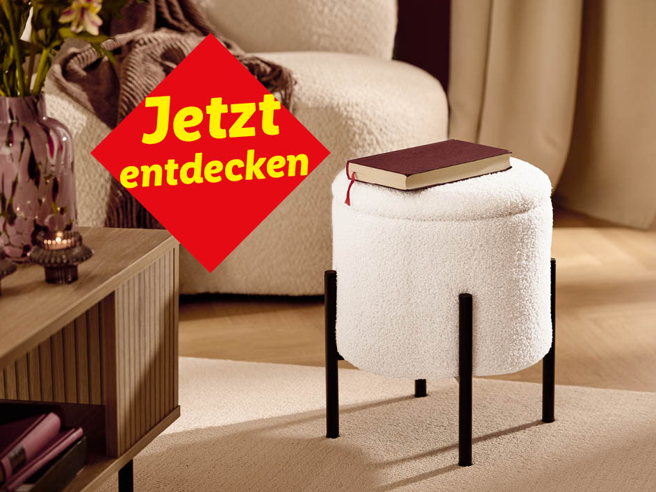 Ein gemütliches Wohnzimmer mit einem weißen Hocker, einem Couchtisch und einem roten Banner.
