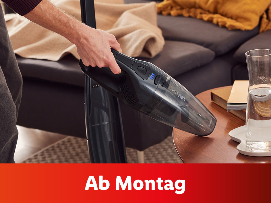 Eine Person benutzt einen handlichen Akkusauger von AEG auf einem Couchtisch.