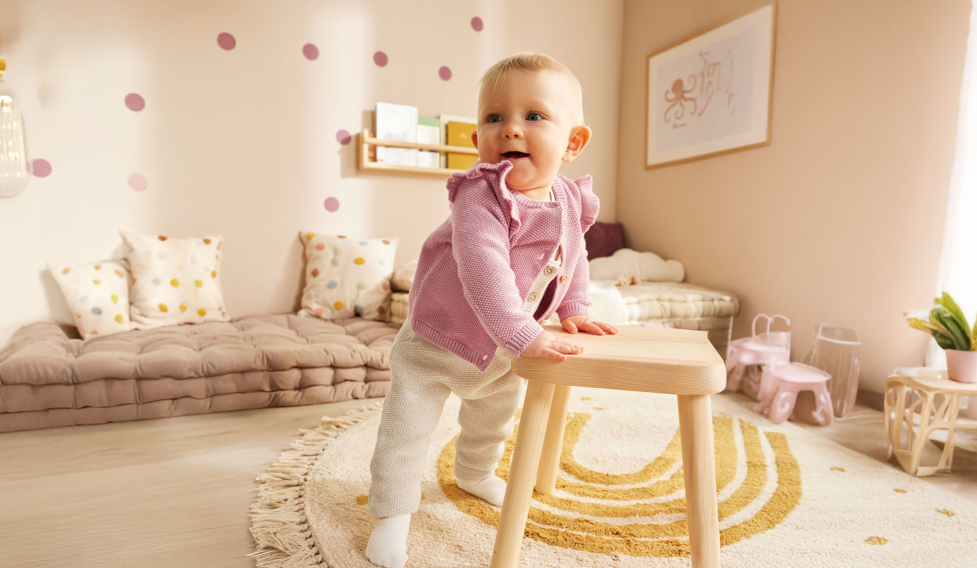 Kleines Kind steht an einem hölzernen Hocker in einem minimalistisch eingerichteten Kinderzimmer.