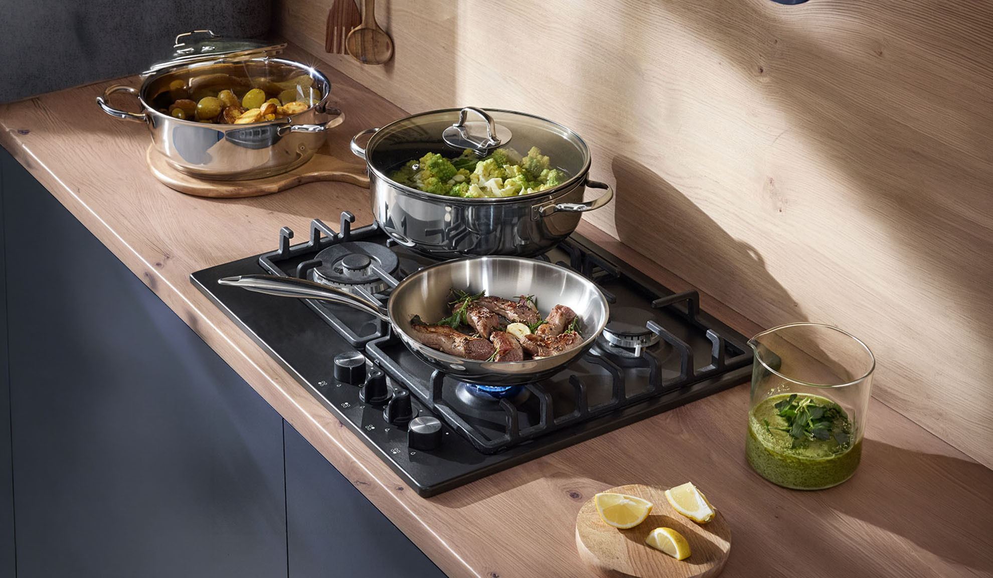 Gasherd mit Pfanne und Töpfen auf einer Holzarbeitsplatte, eine Mahlzeit wird zubereitet.