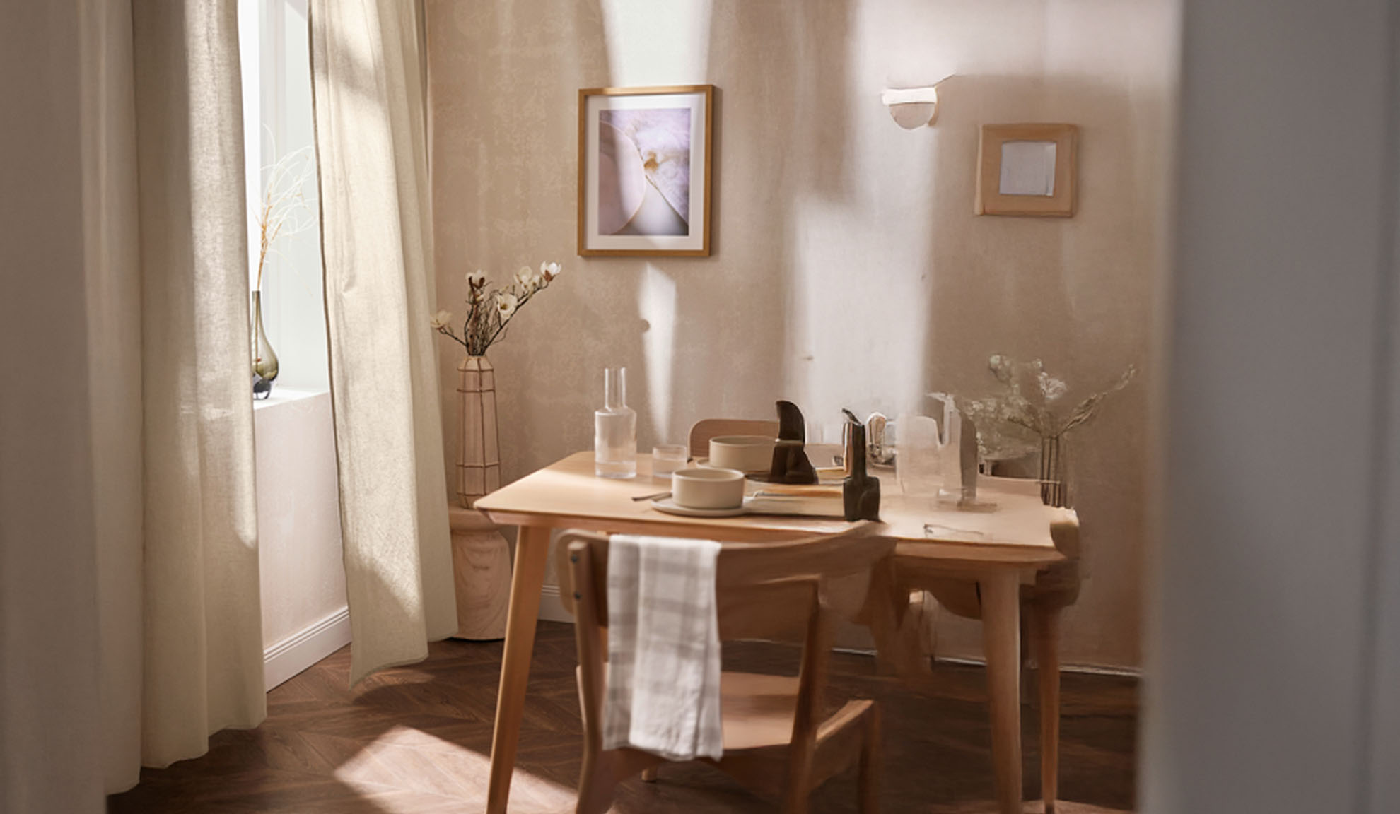 Ein Esszimmer mit einem Holztisch für zwei Personen, heller Einrichtung und natürlichem Licht.