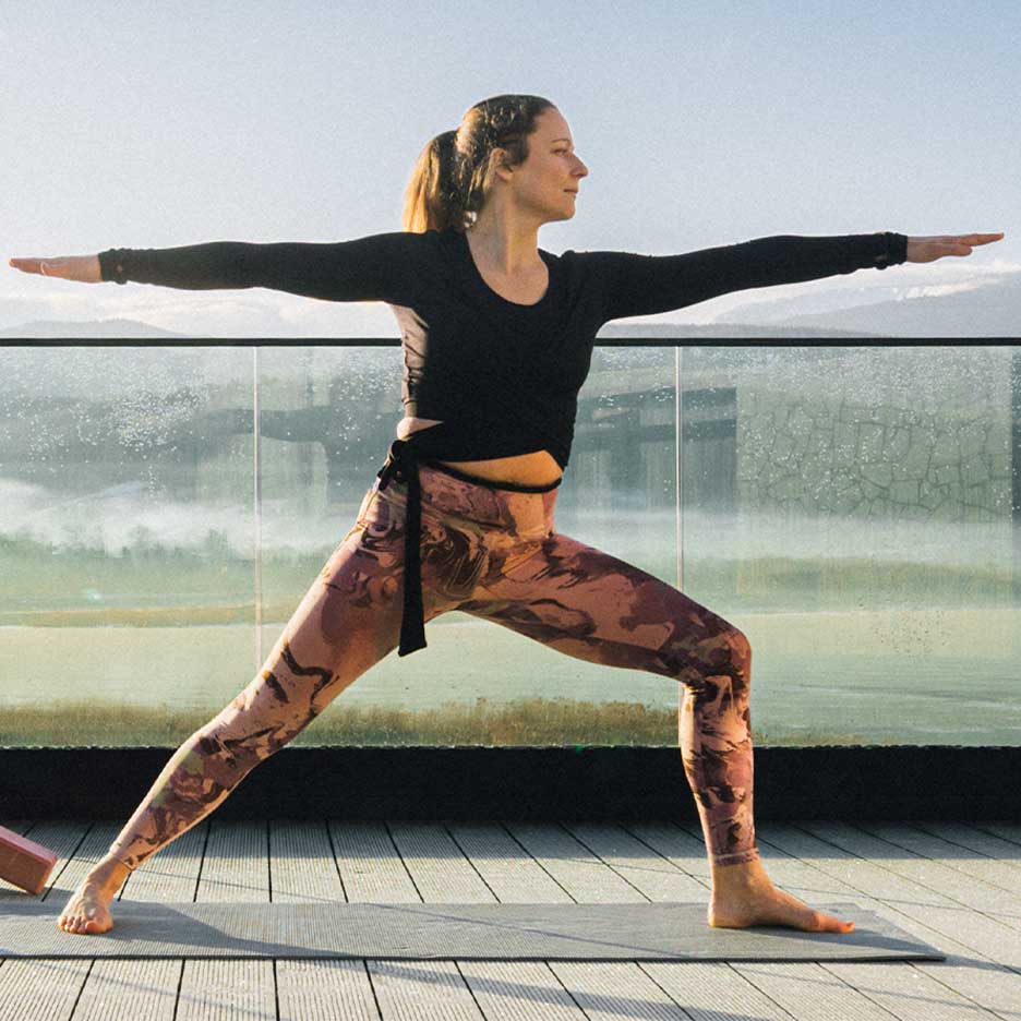 Frau in Leggings und Yoga-Top auf einer Terrasse