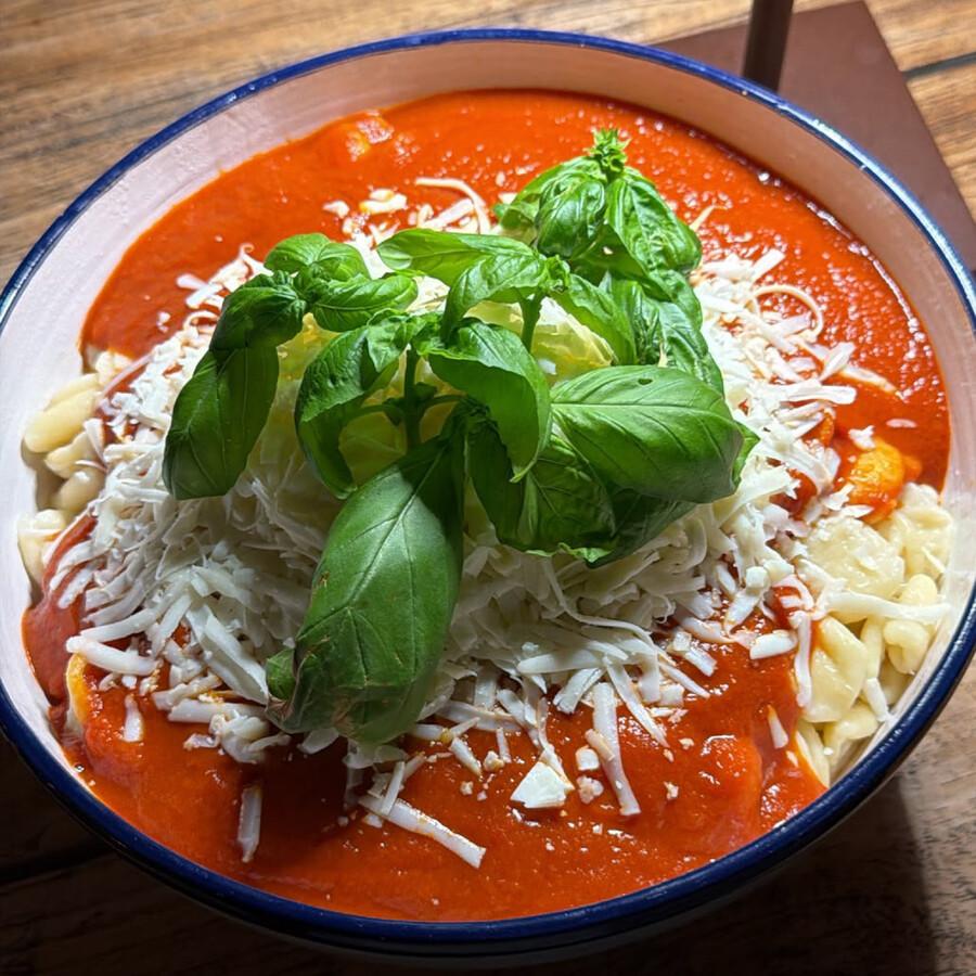 Pasta mit Tomatensauce, geriebenem Käse und frischem Basilikum in einer Schüssel.