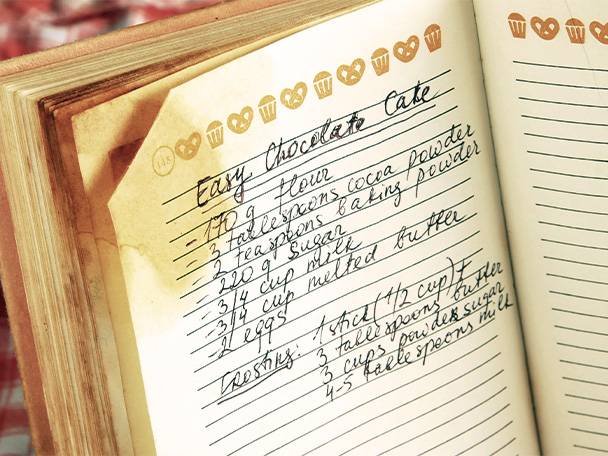 Ein altes Rezeptbuch mit einem handschriftlichen Rezept für einen einfachen Schokoladenkuchen.