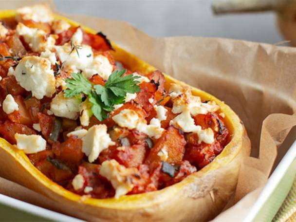 Gefüllter Butternusskürbis mit Tomaten, Kräutern und Feta in einer Auflaufform.
