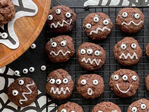 Schokoladenkekse mit gruseligen Augen und Zuckerguss auf einem Drahtgitter.