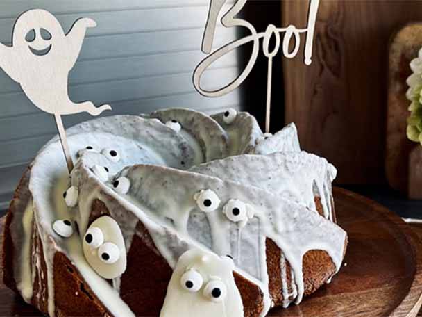 Ein Halloween-Kuchen mit weißer Glasur, Zuckeraugen und zwei „Boo!“- und Geister-Toppern.