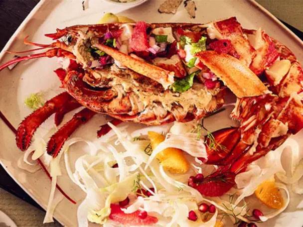 Gegrillter Hummer mit frischem Salat und Granatapfelkernen auf einem Teller