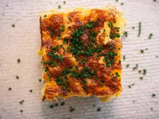 Goldbrauner Kartoffelauflauf mit Schnittlauch auf hellem Untergrund