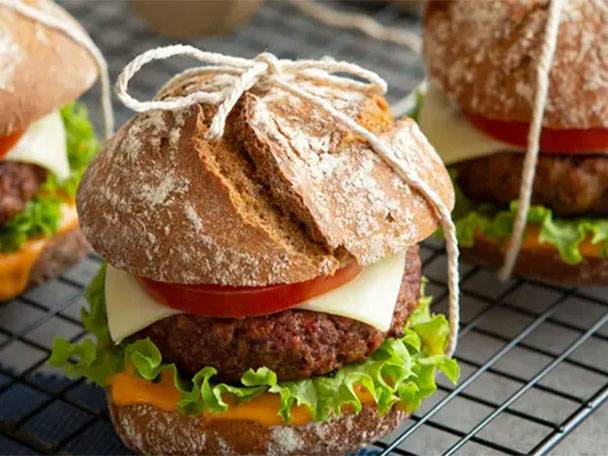 Zwei Burger mit Käse, Tomaten und Salat auf einem Gitterrost.