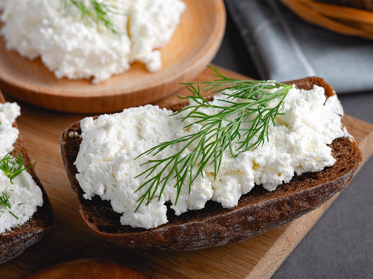 Frischkäse auf dunklem Brot mit Dill garniert.