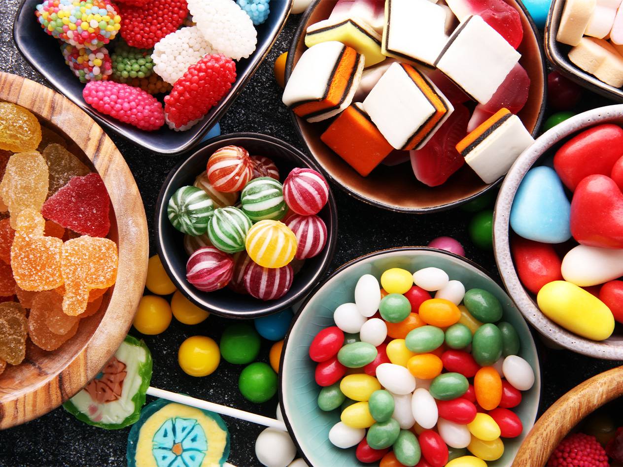 Eine bunte Auswahl an Süßigkeiten, darunter Gummibärchen, Bonbons und Schokolinsen.