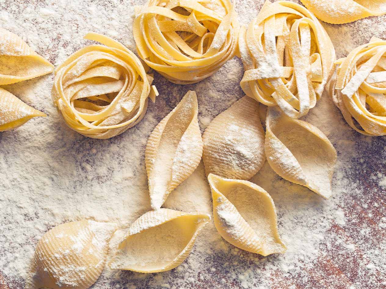 Verschiedene Nudelsorten, darunter Tagliatelle und Conchiglie, mit Mehl bestäubt.