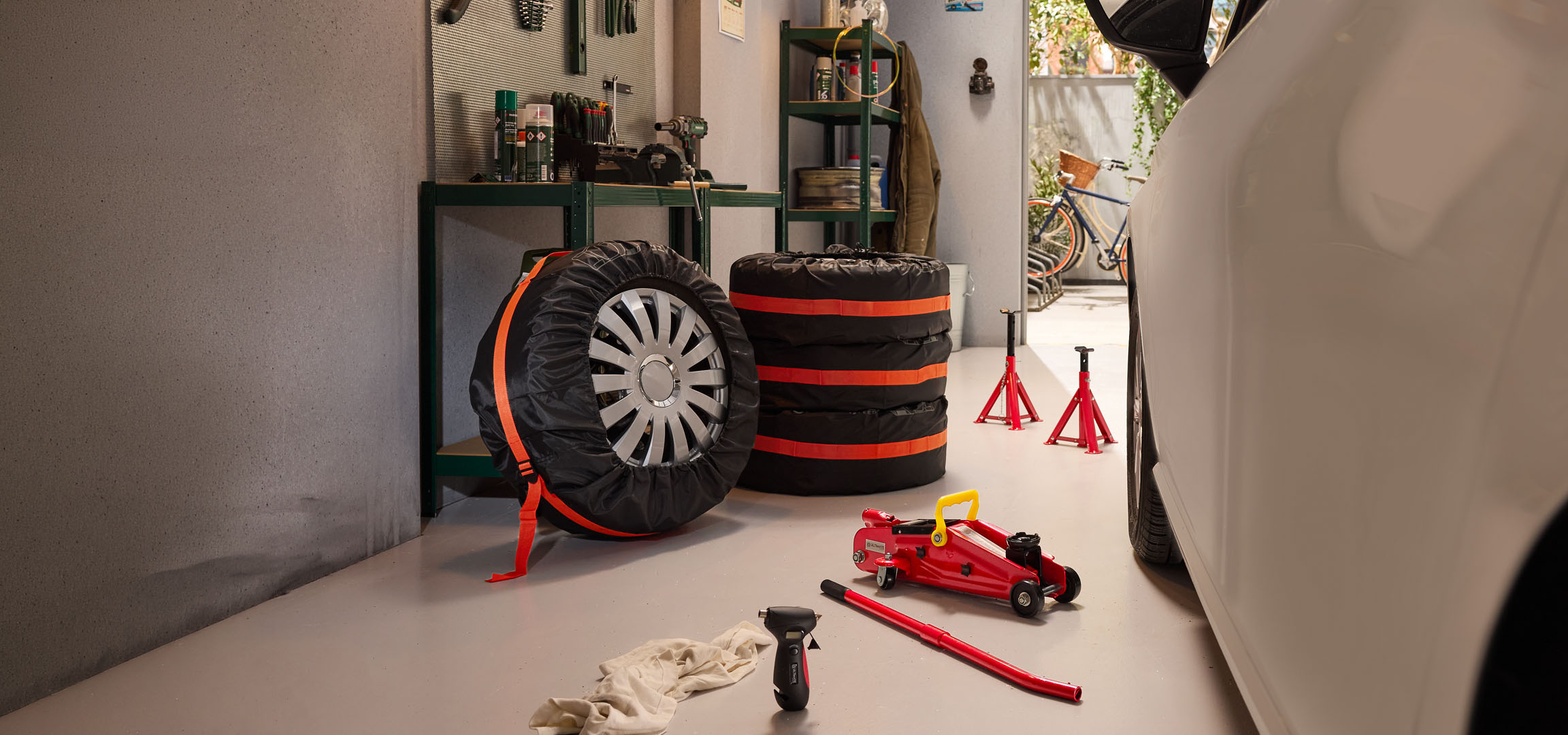 Winterreifen in einer Garage gelagert mit Wagenheber und Unterstellböcken.